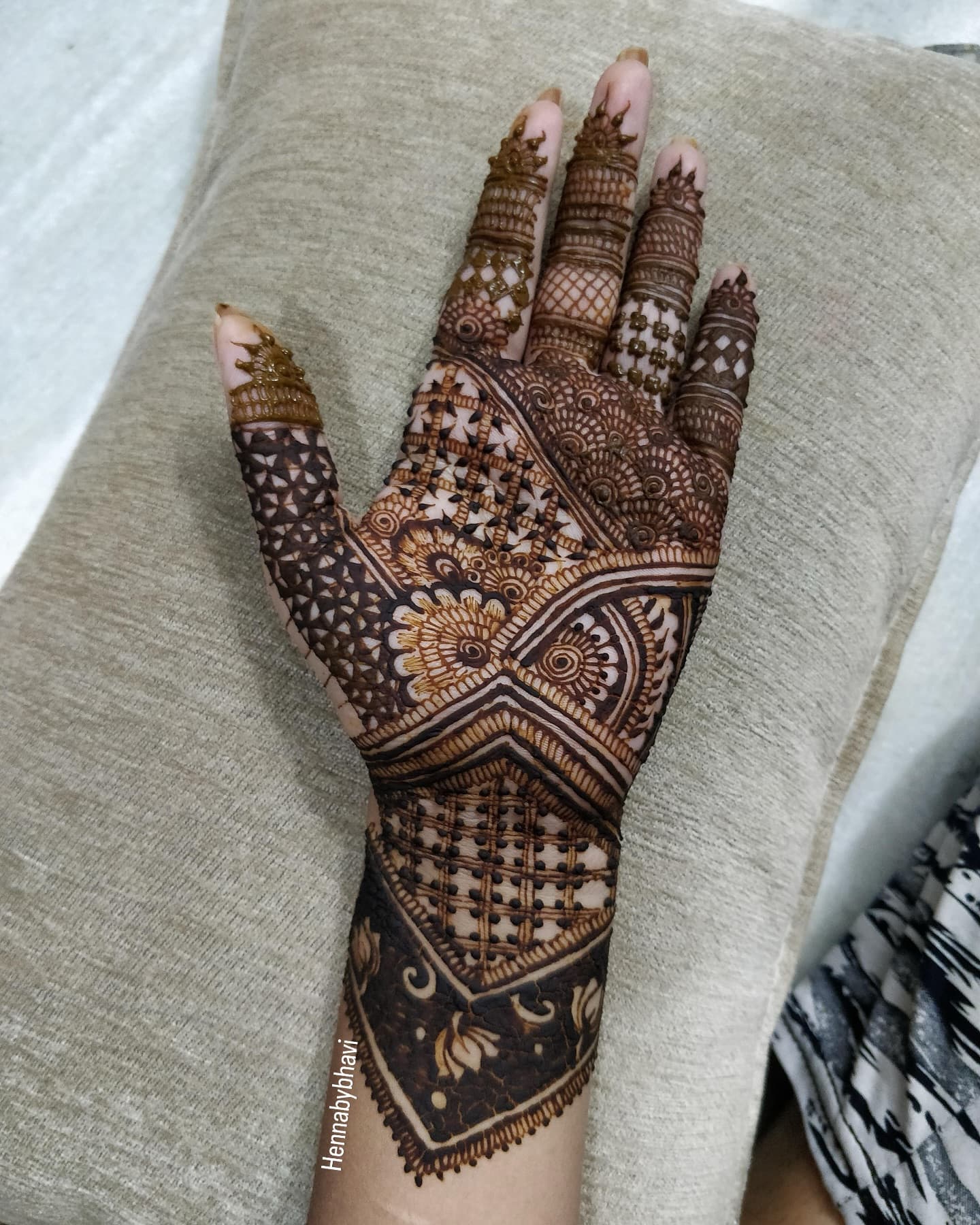 A palm covered in an intricate geometric and floral bridal henna design